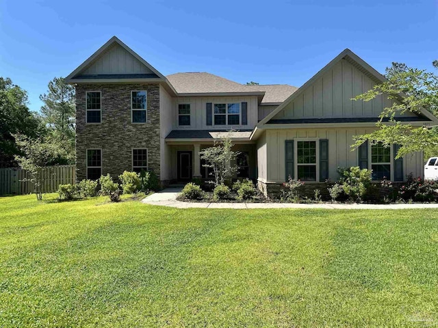 craftsman-style home featuring a front lawn, board and batten siding, fence, and stone siding