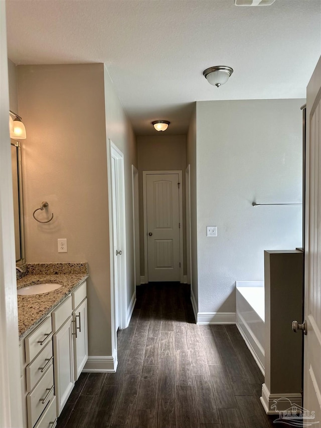 bathroom featuring vanity, baseboards, a washtub, and wood finished floors