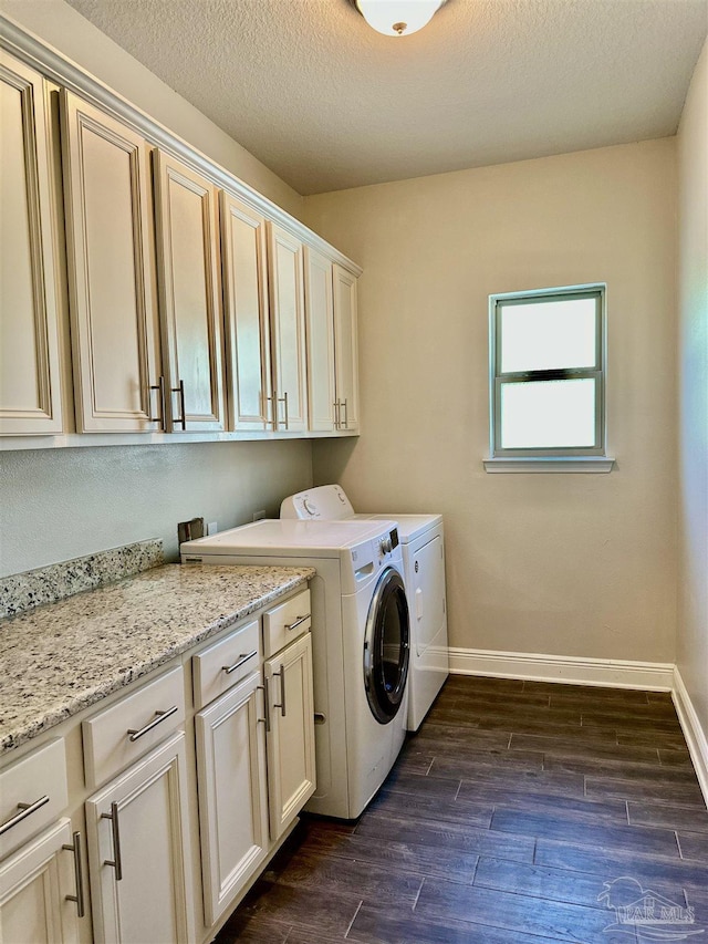 washroom featuring cabinet space, dark wood-style flooring, washer and dryer, a textured ceiling, and baseboards