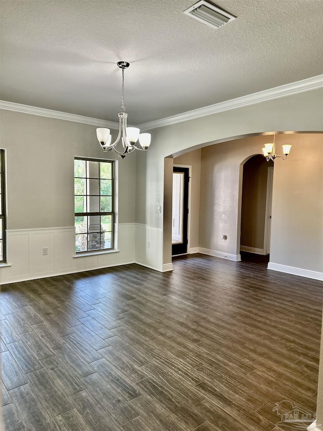 empty room featuring crown molding, arched walkways, visible vents, and a chandelier