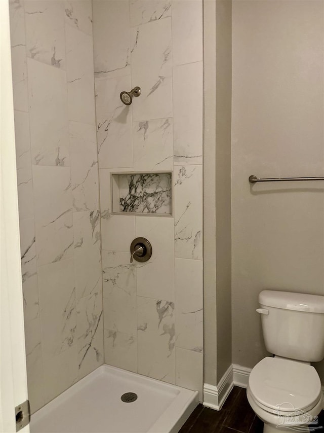 bathroom featuring toilet, baseboards, and a shower stall