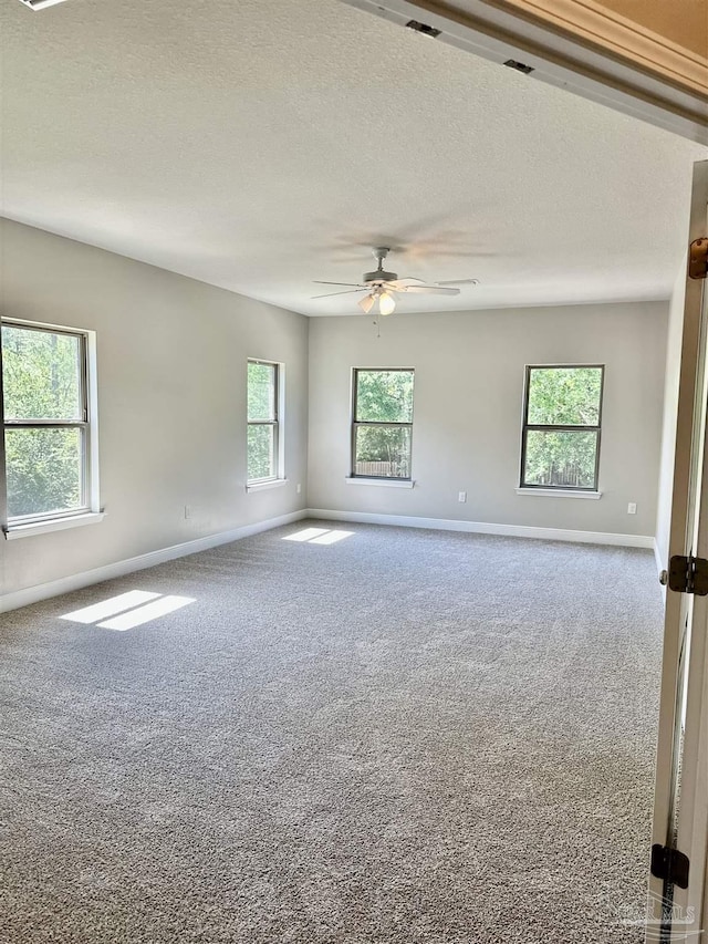 carpeted spare room with baseboards, a textured ceiling, and ceiling fan