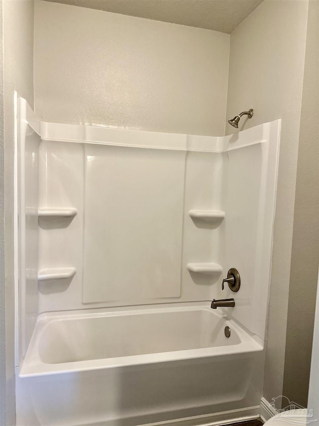 bathroom featuring a textured wall and shower / bathing tub combination