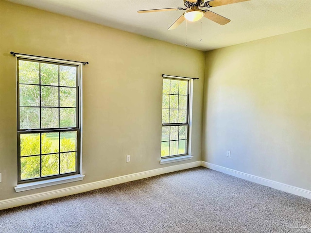carpeted spare room featuring baseboards and ceiling fan