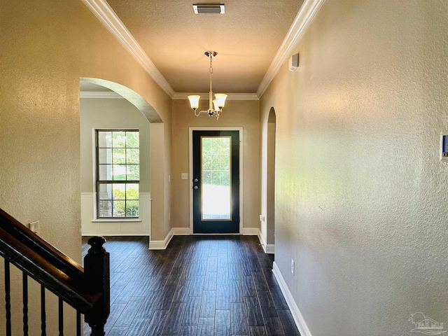 doorway with arched walkways, a textured wall, visible vents, and dark wood finished floors