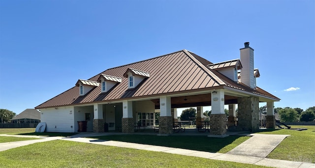 exterior space featuring fence, stone siding, a front yard, a standing seam roof, and metal roof