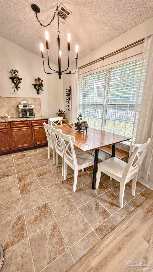 dining area featuring a chandelier, a textured ceiling, and light hardwood / wood-style floors