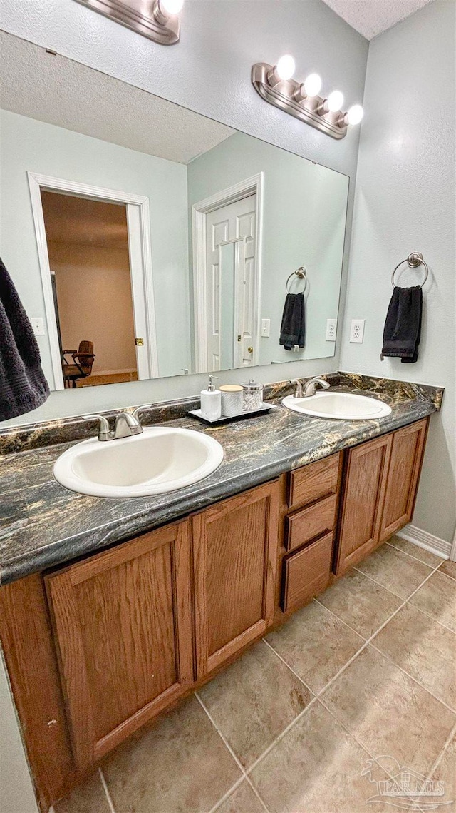 bathroom with tile patterned flooring, a textured ceiling, and vanity