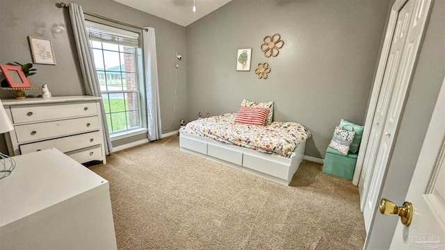 bedroom featuring a closet, light colored carpet, and lofted ceiling