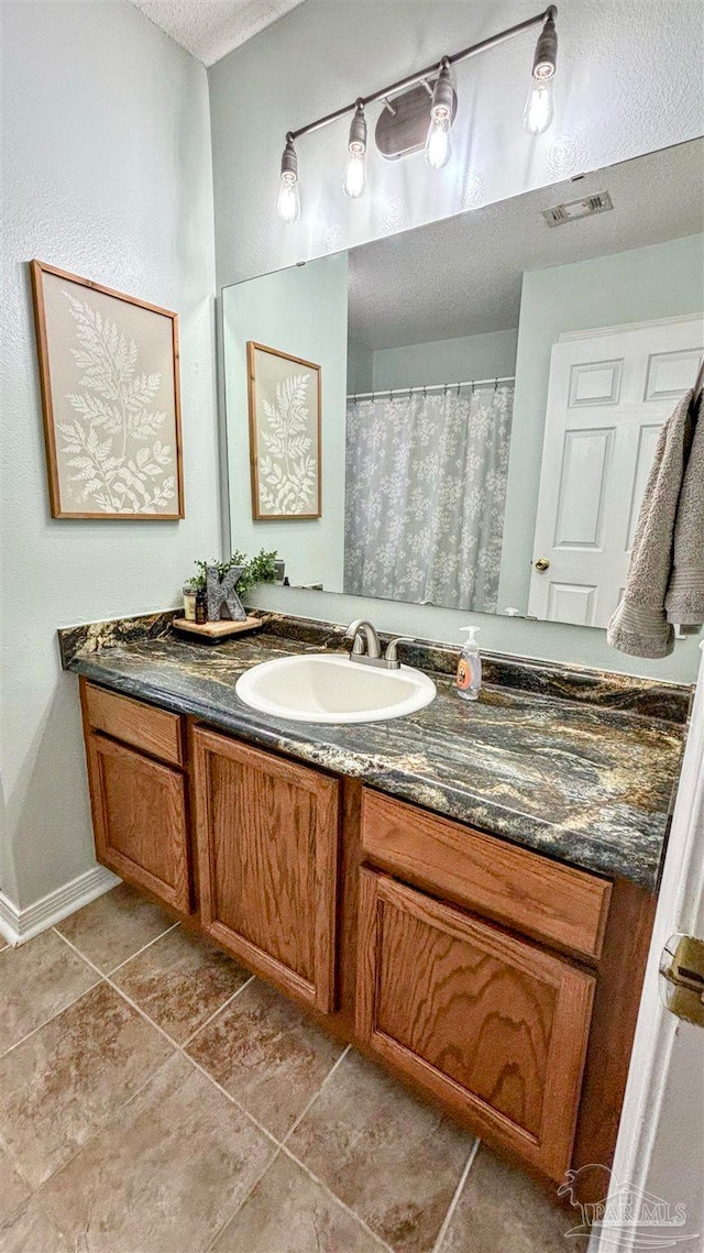 bathroom featuring tile patterned flooring, vanity, and a textured ceiling