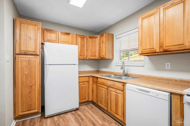 kitchen with light wood finished floors, light countertops, white appliances, and a sink