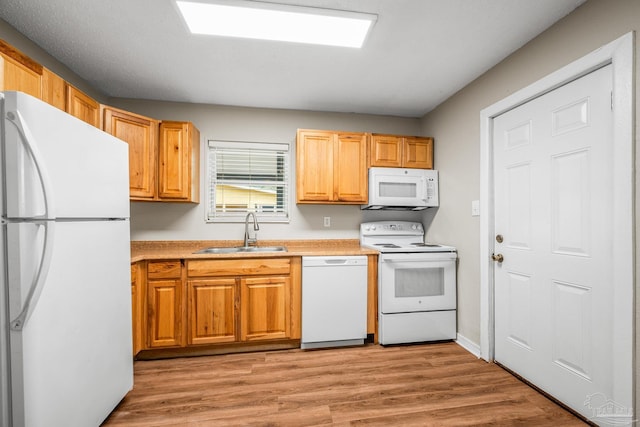 kitchen with white appliances, light countertops, a sink, and light wood finished floors