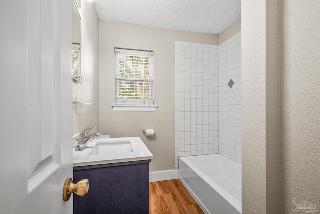 full bathroom with baseboards, wood finished floors, bathtub / shower combination, a textured ceiling, and vanity