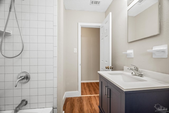 bathroom with bathtub / shower combination, visible vents, vanity, wood finished floors, and baseboards