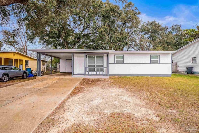 ranch-style house with concrete driveway, an attached carport, and a front lawn