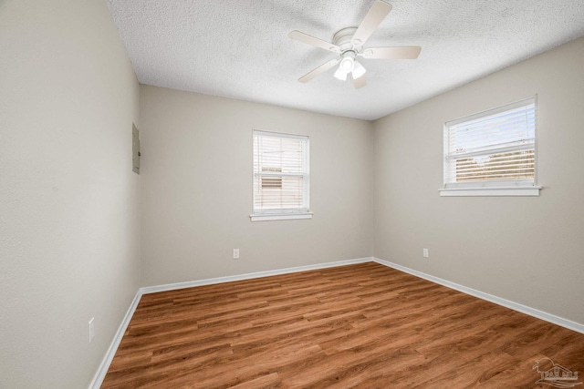 spare room with a textured ceiling, ceiling fan, wood finished floors, and baseboards