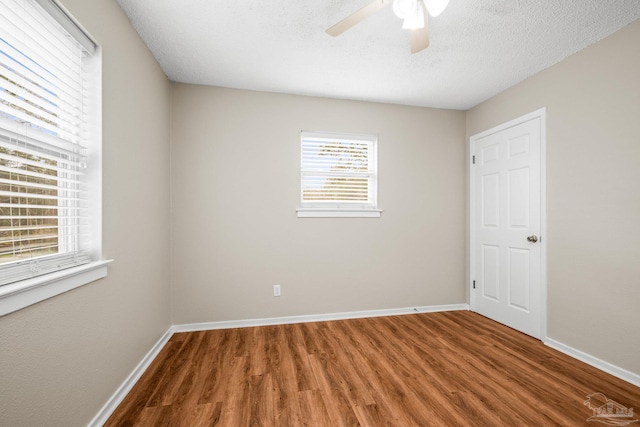 unfurnished bedroom featuring a ceiling fan, a textured ceiling, baseboards, and wood finished floors