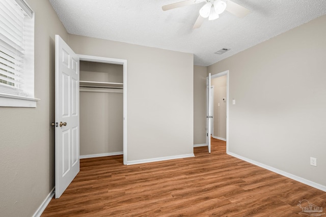 unfurnished bedroom with a textured ceiling, baseboards, and wood finished floors