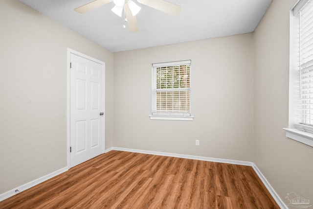 unfurnished room with ceiling fan, a textured ceiling, baseboards, and wood finished floors