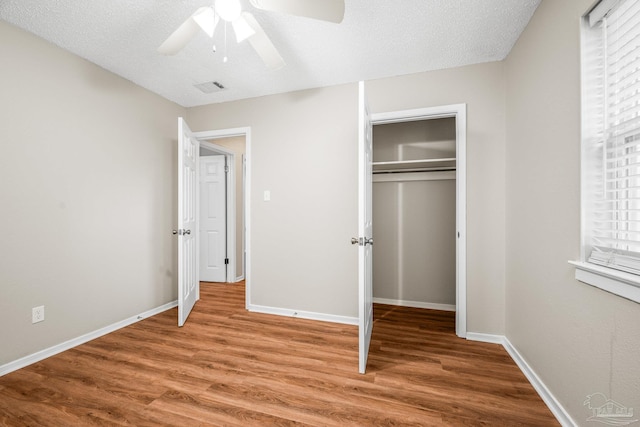 unfurnished bedroom featuring a closet, visible vents, baseboards, and wood finished floors