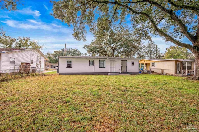 rear view of house with a yard and fence