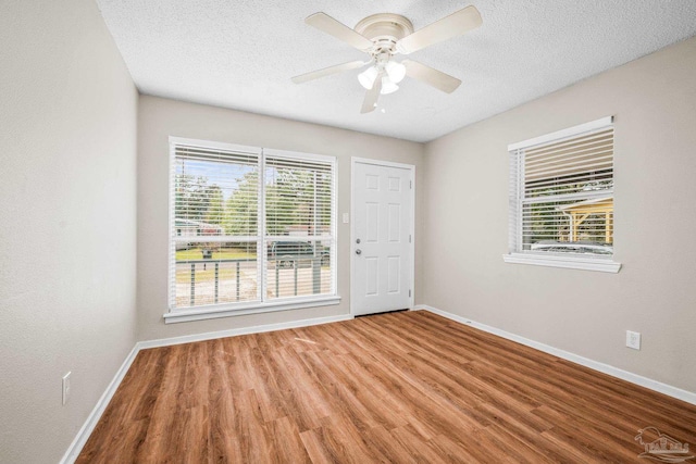 spare room with ceiling fan, a textured ceiling, baseboards, and wood finished floors