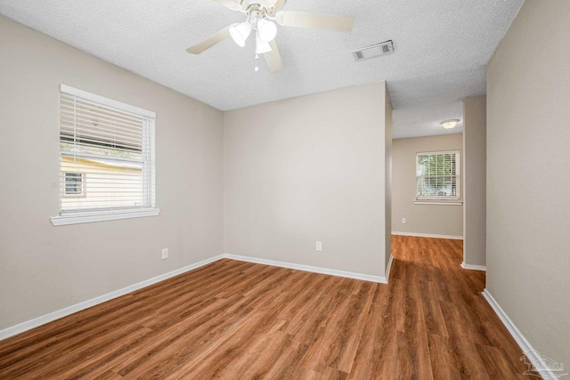 unfurnished room featuring baseboards, a textured ceiling, visible vents, and dark wood-type flooring