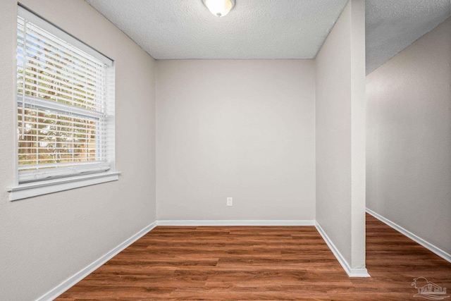 unfurnished room with dark wood-style floors, a textured ceiling, and baseboards