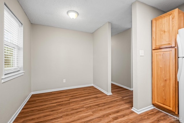 spare room featuring a textured ceiling, wood finished floors, and baseboards