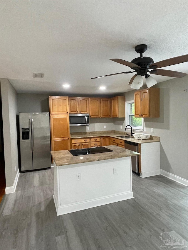 kitchen featuring ceiling fan, sink, a center island, stainless steel appliances, and dark hardwood / wood-style flooring