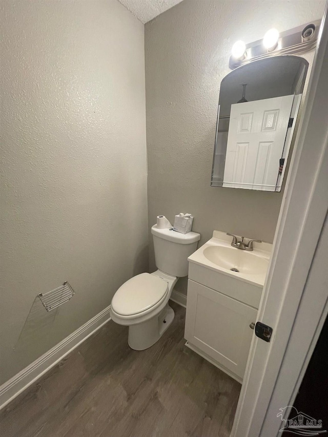 bathroom featuring wood-type flooring, vanity, a textured ceiling, and toilet