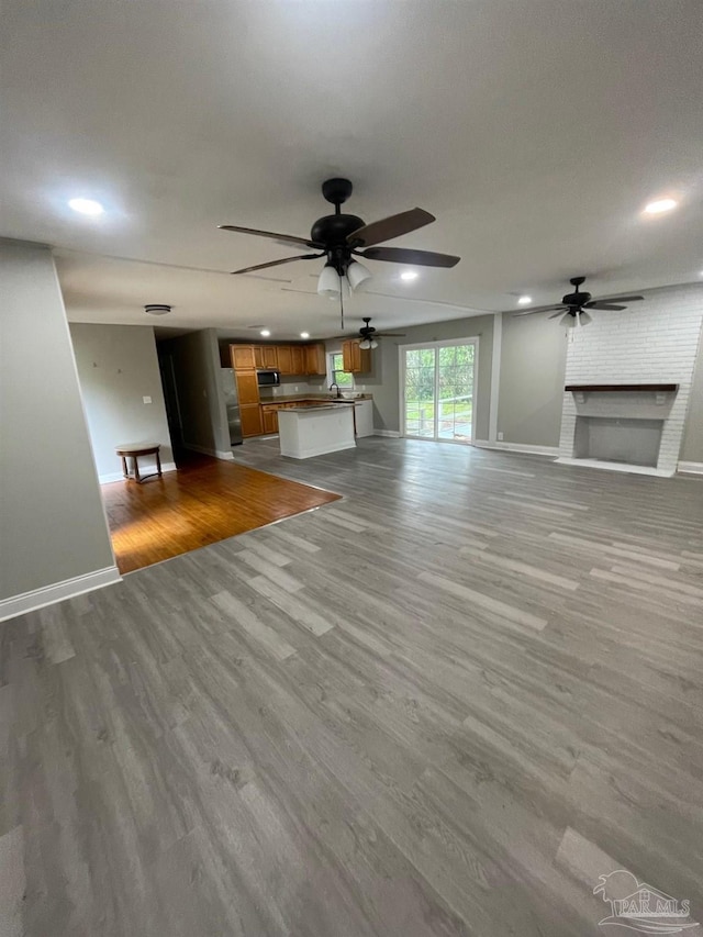 unfurnished living room featuring a fireplace, light hardwood / wood-style flooring, and ceiling fan