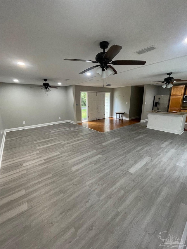 unfurnished living room with ceiling fan and light hardwood / wood-style flooring