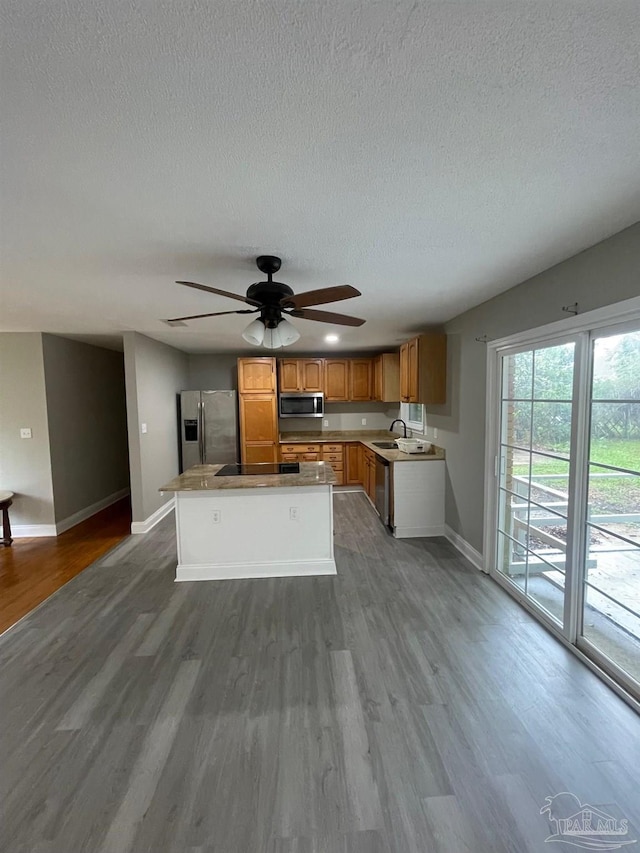 kitchen featuring sink, ceiling fan, a textured ceiling, appliances with stainless steel finishes, and wood-type flooring