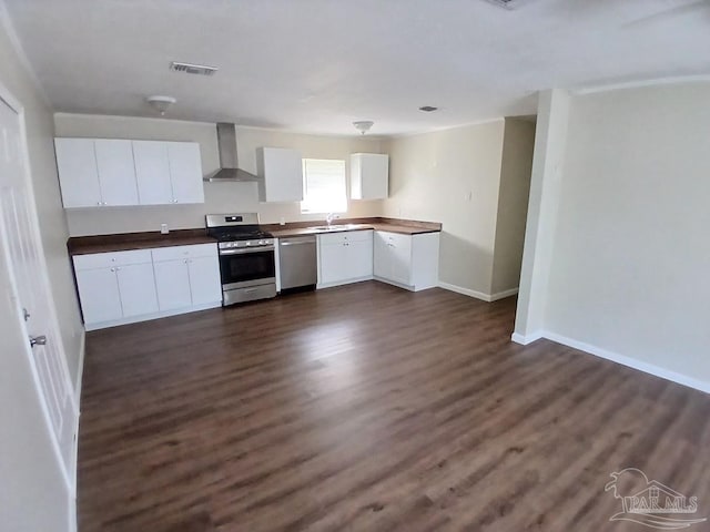 kitchen with white cabinets, appliances with stainless steel finishes, dark wood-type flooring, and wall chimney range hood