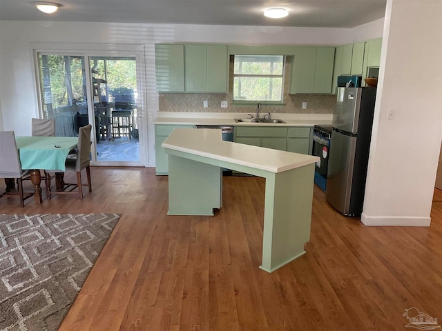 kitchen featuring hardwood / wood-style floors, sink, green cabinetry, stainless steel fridge, and a kitchen island