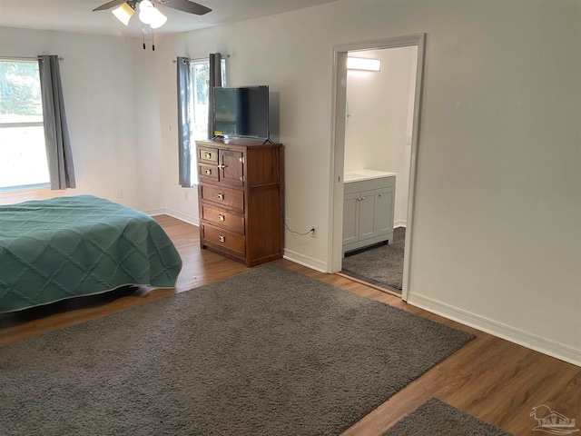 bedroom with ceiling fan, ensuite bathroom, and dark hardwood / wood-style floors