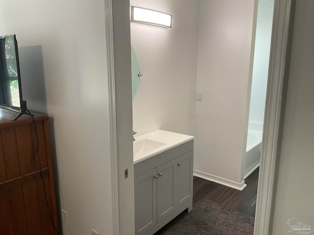 bathroom with hardwood / wood-style floors, vanity, and a bath
