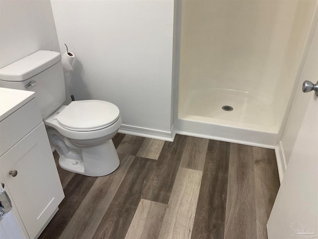 bathroom with hardwood / wood-style flooring, vanity, toilet, and a shower