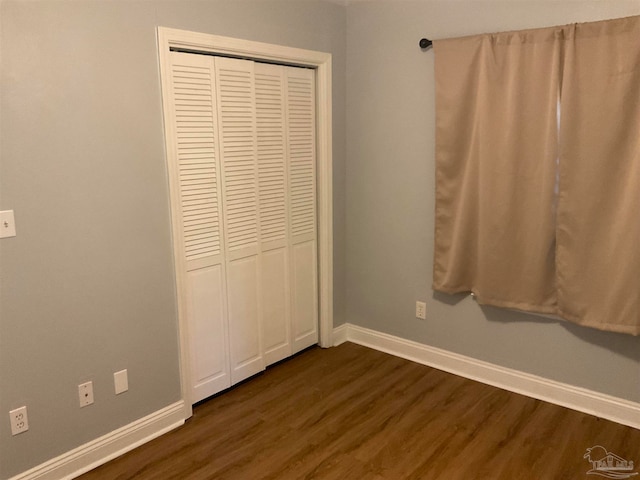 unfurnished bedroom with a closet and dark hardwood / wood-style floors