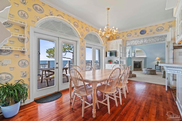 4757 Chinquapin Dr, Gulf Breeze, FL 32563 - dining space featuring french doors, a chandelier, dark wood-style floors, a glass covered fireplace, and wallpapered walls