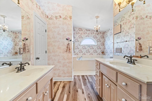 4757 Chinquapin Dr, Gulf Breeze, FL 32563 - bathroom featuring a chandelier, wood finished floors, two vanities, wallpapered walls, and a bath