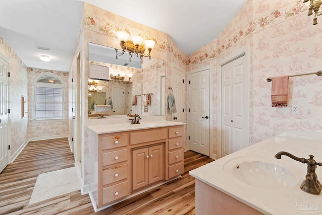 4757 Chinquapin Dr, Gulf Breeze, FL 32563 - full bathroom featuring a chandelier, wallpapered walls, wood finished floors, two vanities, and a closet
