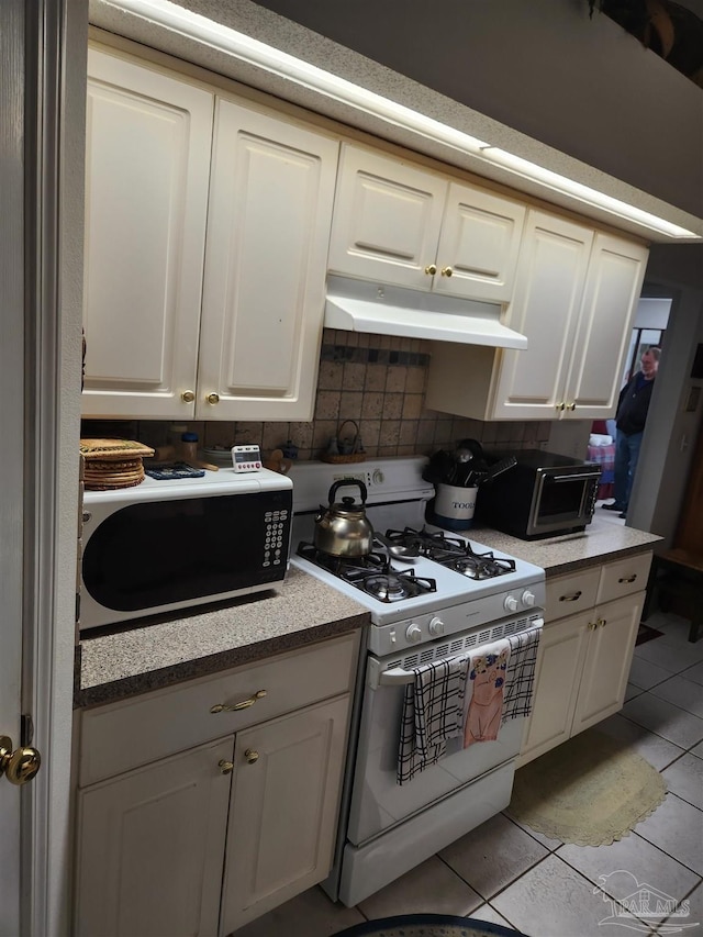 kitchen with light tile patterned floors, white gas range oven, and decorative backsplash