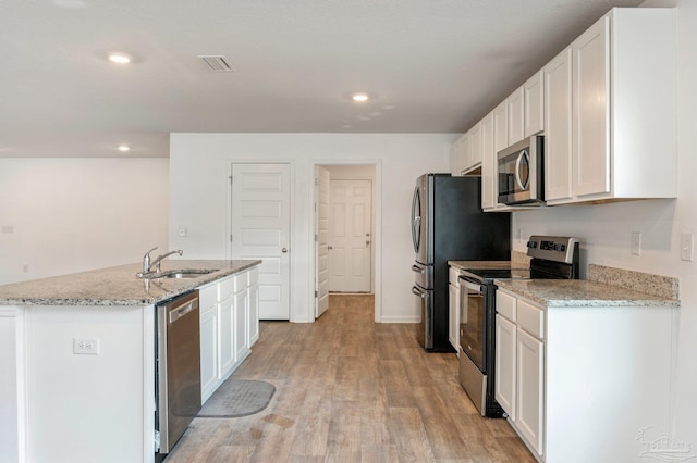 kitchen with stainless steel appliances, sink, white cabinets, and light hardwood / wood-style floors