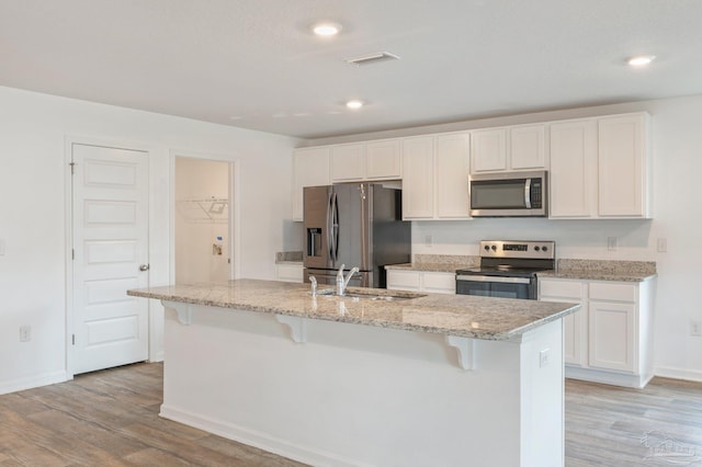 kitchen featuring light wood-type flooring, a kitchen island with sink, stainless steel appliances, and sink