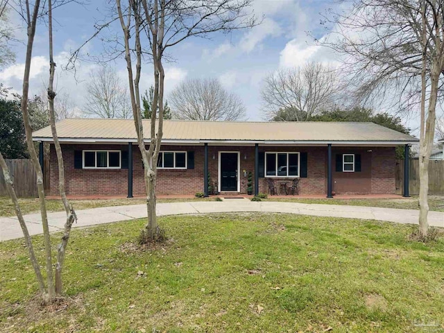 ranch-style house featuring metal roof, fence, a front lawn, and brick siding