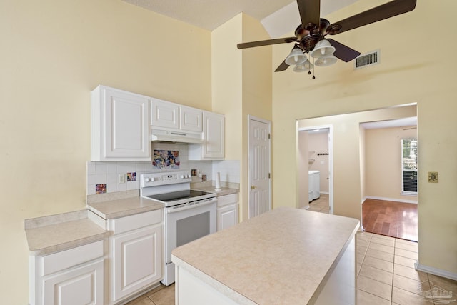 2121 Middleton Dr, Navarre, FL 32566 - kitchen with under cabinet range hood, light tile patterned floors, white electric stove, and visible vents