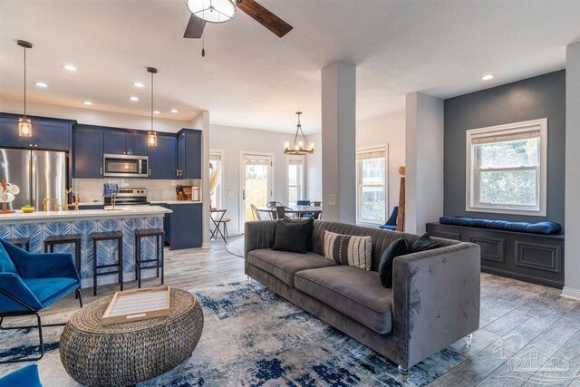 living room with light hardwood / wood-style flooring and ceiling fan with notable chandelier