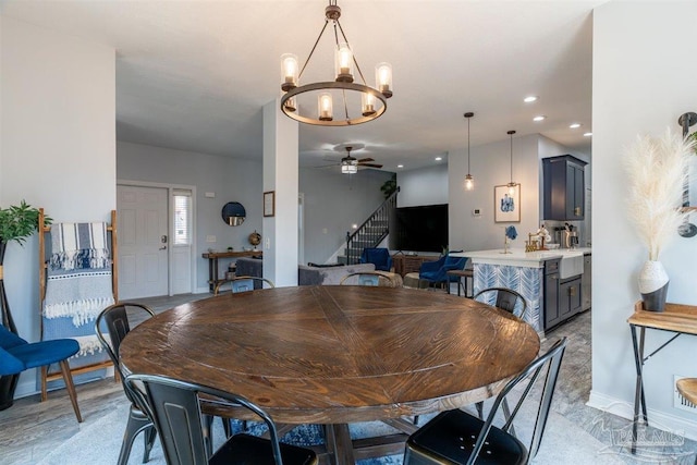 dining area with ceiling fan with notable chandelier and light hardwood / wood-style flooring